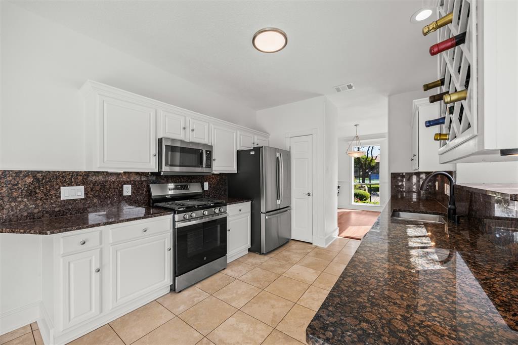 Photograph looking from breakfast area back through kitchen toward dining room.  All new GE appliances including microwave, dishwasher, gas stove with electric oven, GE French Door Refrigerator/freezer drawer.