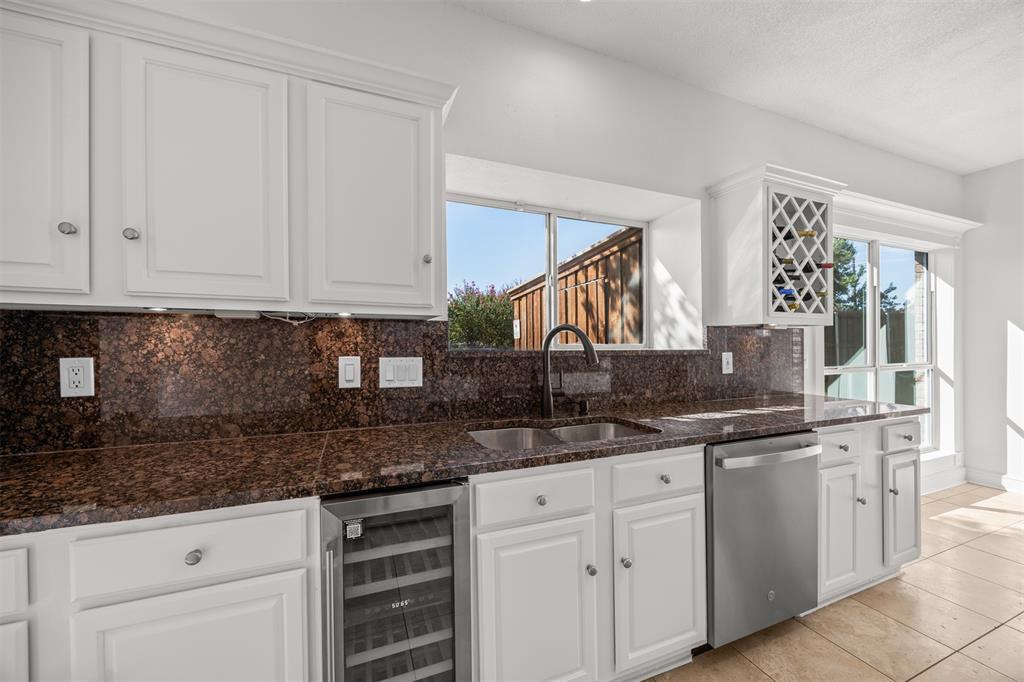 Photograph showing, granite counter top, upper and lower cabinets, new GE dishwasher and under counter beverage refrigerator.
