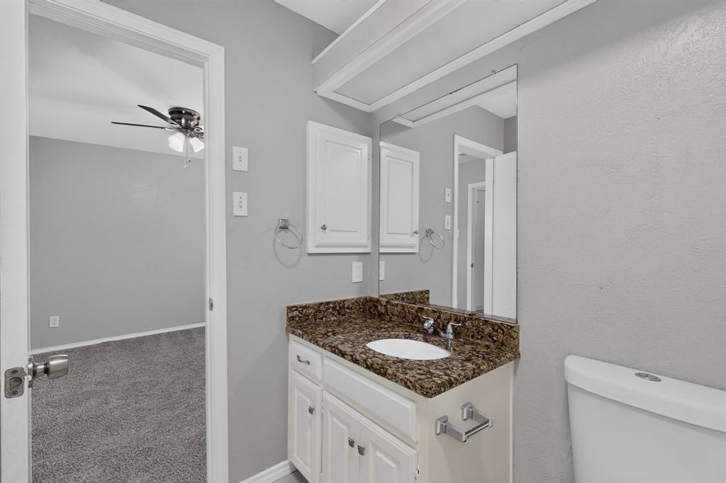 Bathroom vanity with an undermount sink, dark speckled countertop, and white cabinetry