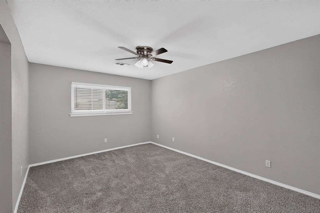 Wall-to-wall carpeting, neutral wall finishes, window with horizontal blinds, and a ceiling fan with integrated lighting