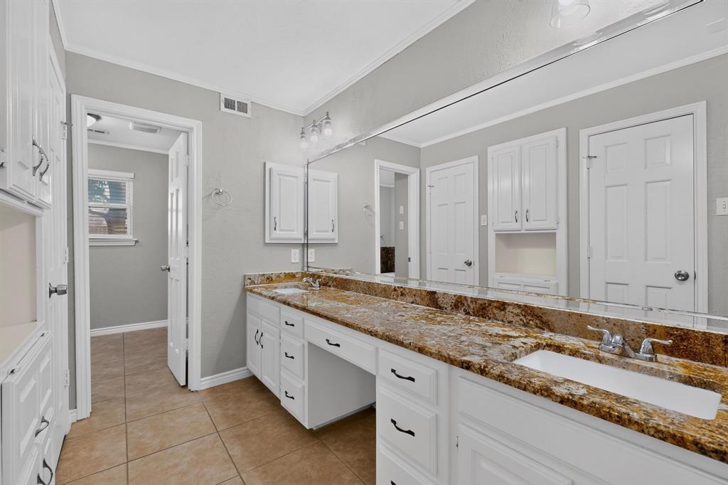 Double vanity with integrated sinks, expansive countertop, white cabinetry, and tile flooring