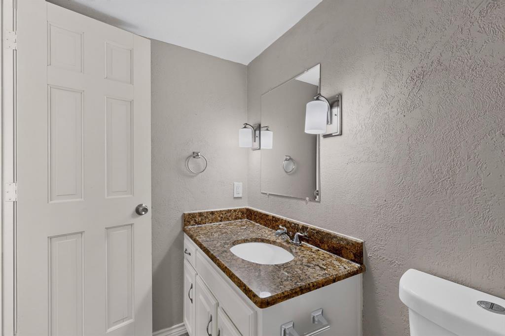 Bathroom vanity with a granite countertop, undermount sink, and chrome faucet