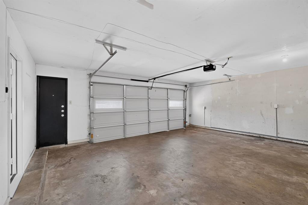 Attached garage with a concrete floor, an overhead garage door, and a black entry door