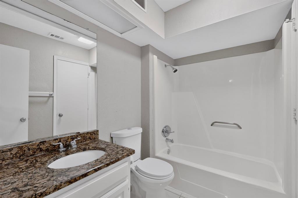 Vanity with a polished stone countertop and integrated sink, chrome faucet, white cabinetry, and a full-width mirror