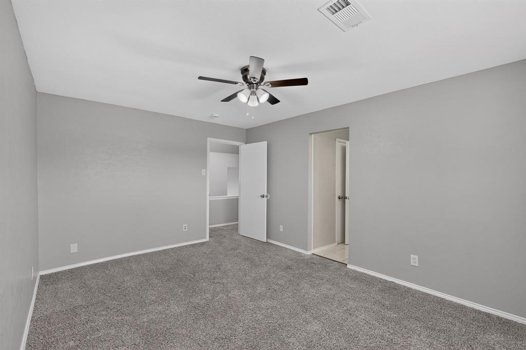 Neutral gray wall finish, gray carpet flooring, ceiling fan with light fixture, white trim, and white interior doors