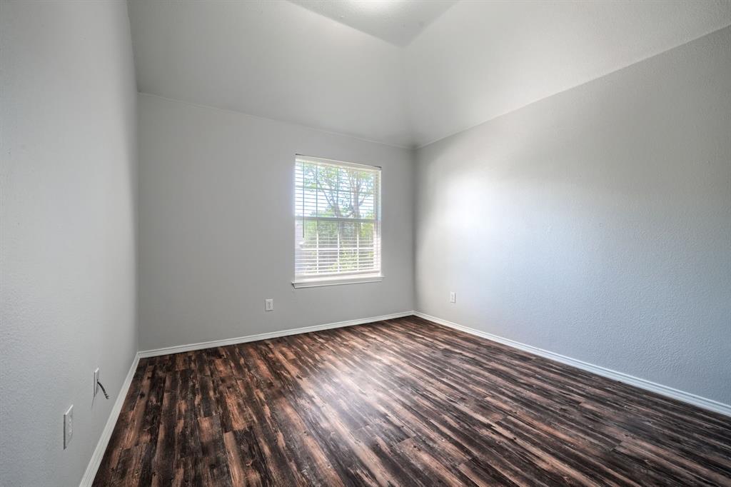 Vaulted ceiling, wood-finish flooring, white window blinds, and light gray wall paint