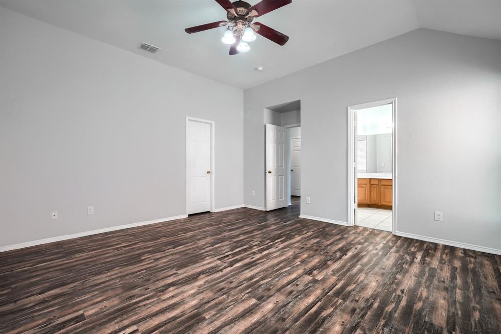 Vaulted ceiling with a ceiling fan, wood-finish flooring, and white interior doors