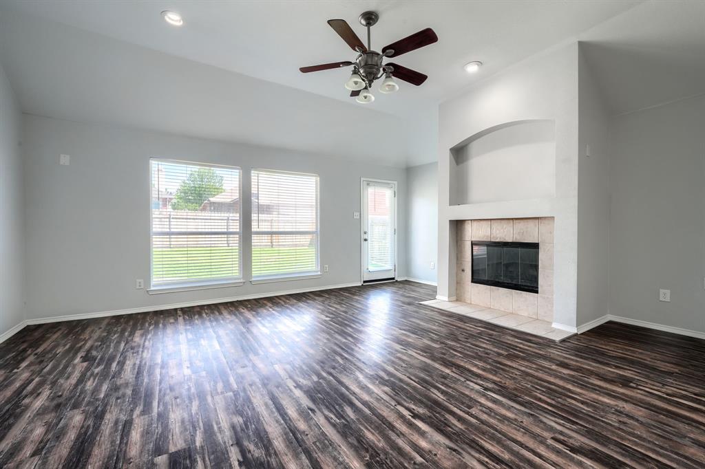 Vaulted ceilings with recessed lighting, wood-finish flooring, a fireplace with a tiled surround, a built-in arched alcove, and multiple windows