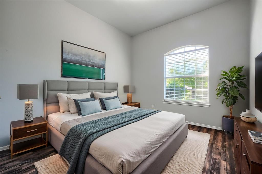 Arched window with blinds, vaulted ceiling, wood-finish flooring, and built-in closet