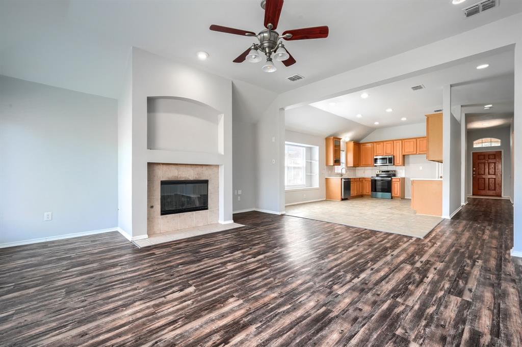 Spacious living area featuring wood-finish flooring, a built-in fireplace with a stone surround, and an integrated display niche