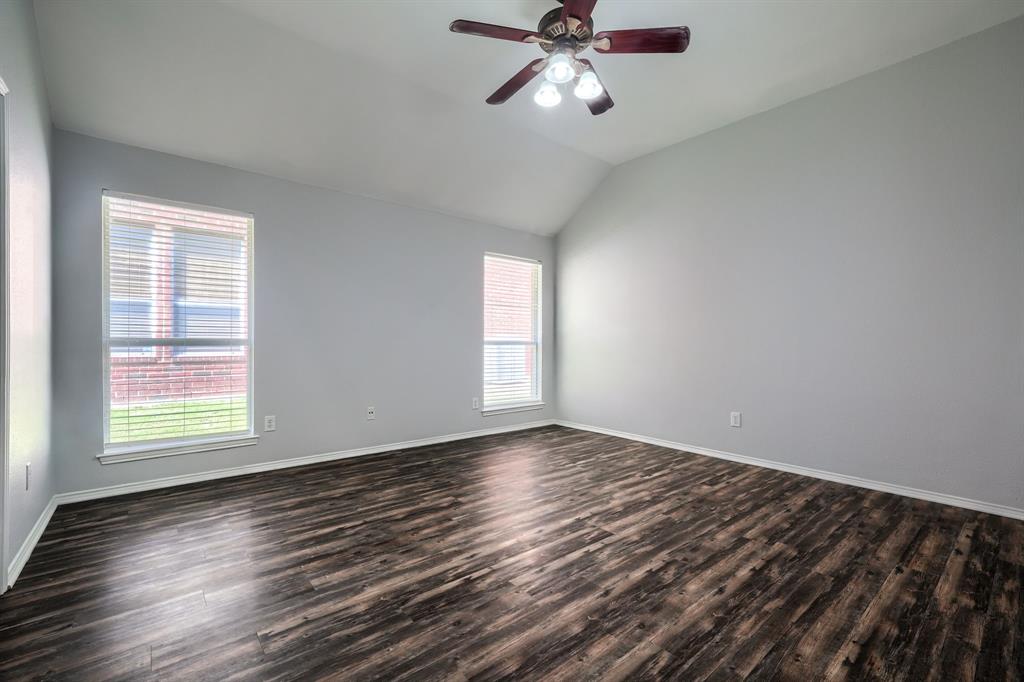 Vaulted ceiling featuring a ceiling fan with integrated lighting, two windows with blinds, and wood-finish flooring