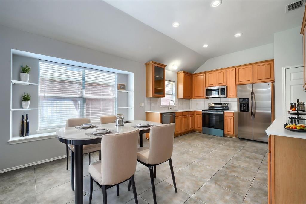 Recessed lighting illuminates the kitchen and dining area with tile flooring