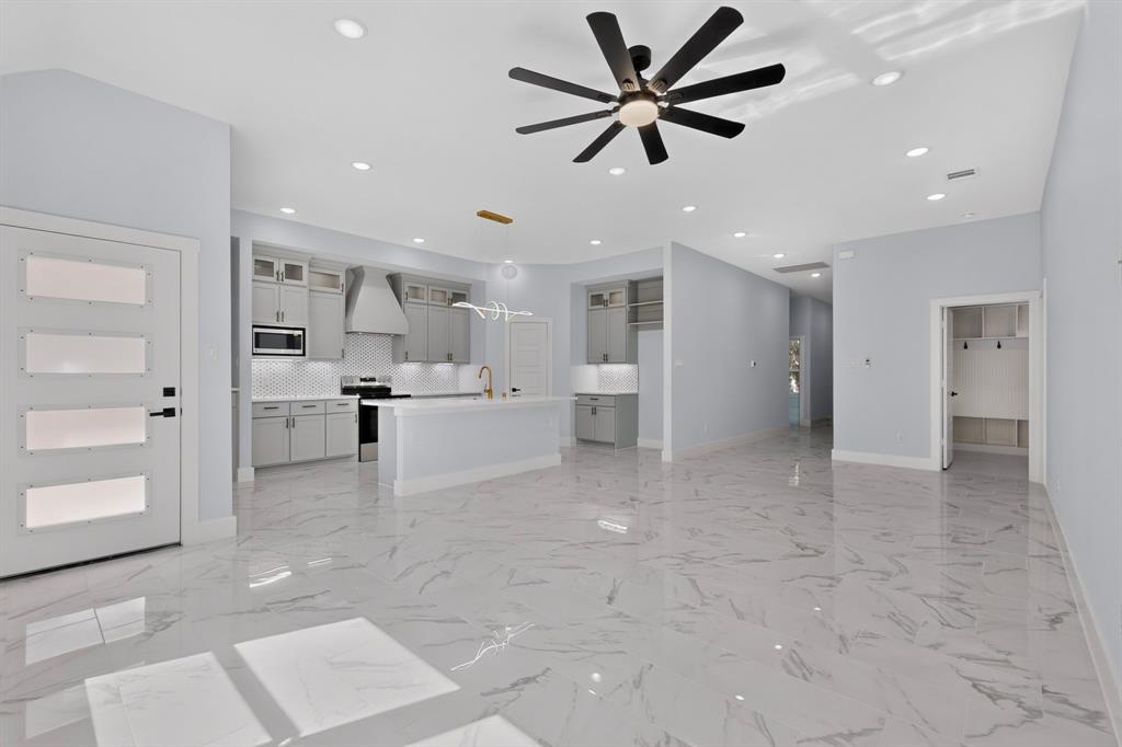 Spacious open-concept living area featuring large format tile flooring, recessed lighting, and a contemporary ceiling fan