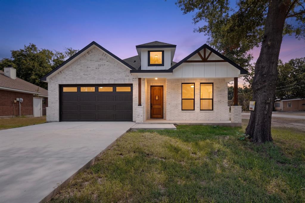 Modern farmhouse exterior featuring light-colored brick, dark trim, and a prominent wood-finish entry door Modern farmhouse exterior featuring light-colored brick, dark trim, and a prominent wood-finish entry door