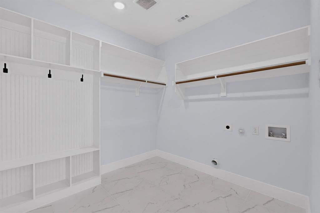 Utility room featuring built-in shelving, hanging rods, and tile flooring