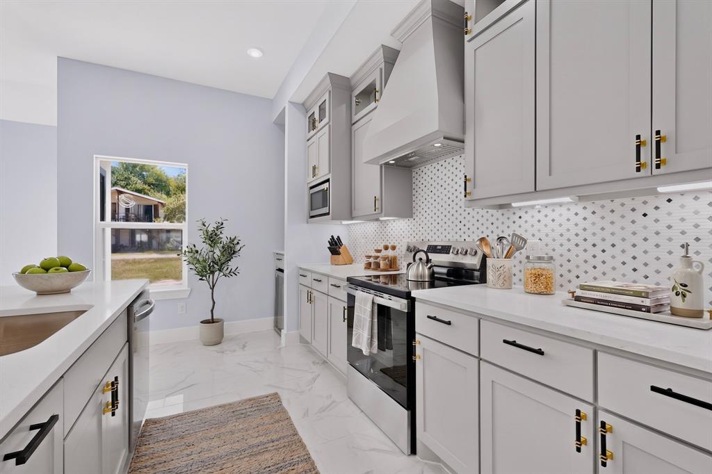 White quartz countertops, light gray cabinetry, stainless steel appliances, patterned tile backsplash, and recessed lighting White quartz countertops, light gray cabinetry, stainless steel appliances, patterned tile backsplash, and recessed lighting