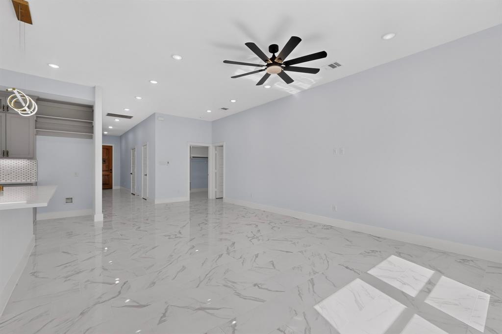 Spacious room with large format tile flooring, recessed lighting, and a contemporary ceiling fan