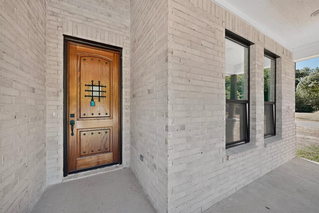 Whitewashed brick exterior with a wood-panel entry door featuring decorative metalwork Whitewashed brick exterior with a wood-panel entry door featuring decorative metalwork