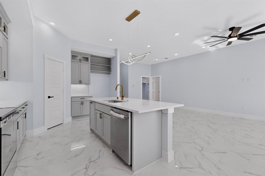 Kitchen featuring a center island with sink, stainless steel dishwasher, white countertops, and gray cabinetry