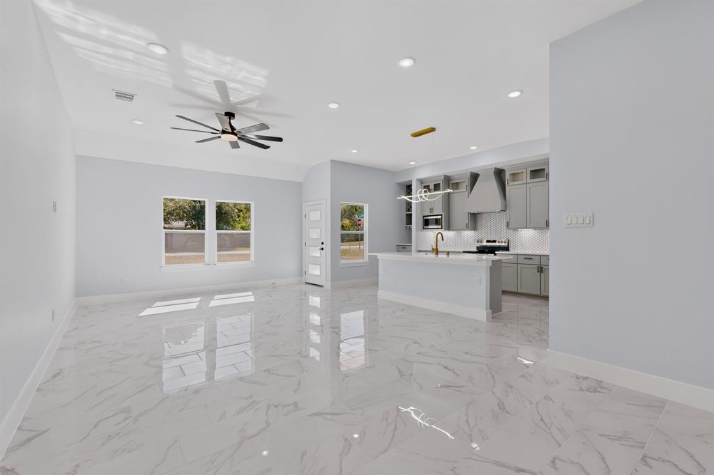 Open concept living space featuring polished tile flooring, recessed lighting, a ceiling fan, and a kitchen with an island and pendant lighting