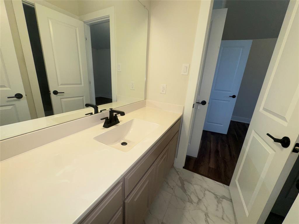 White vanity with a single basin, matte black faucet, and white countertop