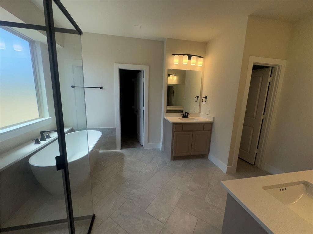 Freestanding soaking tub with matte black fixtures, glass-enclosed shower, dual vanity, and tiled flooring Freestanding soaking tub with matte black fixtures, glass-enclosed shower, dual vanity, and tiled flooring
