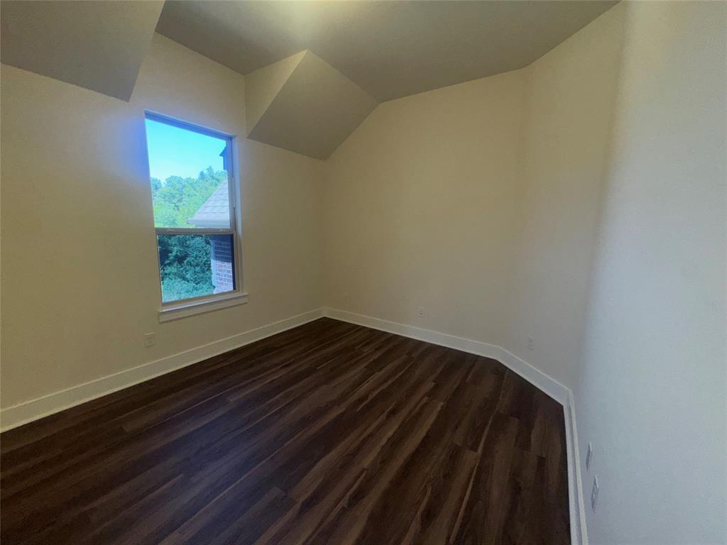 Light-filled room featuring sloped ceilings and wood-finish flooring