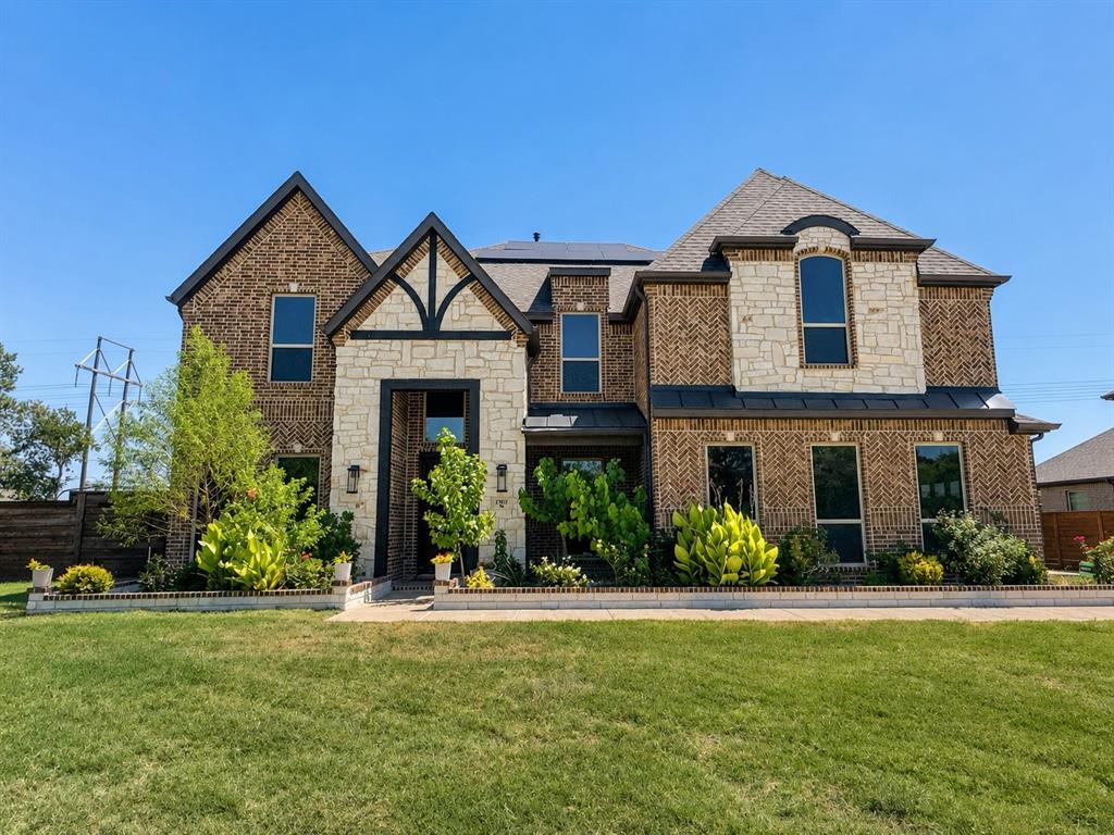 Brick and stone exterior with dark trim accents, multiple gabled rooflines, and a well-maintained lawn Brick and stone exterior with dark trim accents, multiple gabled rooflines, and a well-maintained lawn
