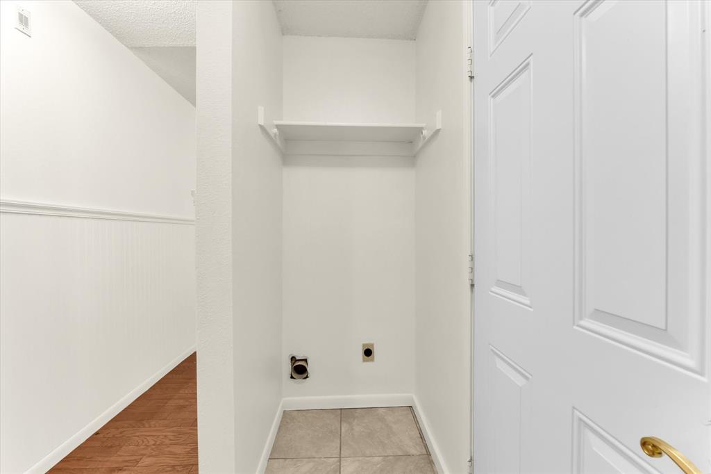 Laundry area with tile flooring, wall-mounted shelving, and plumbing hookups
