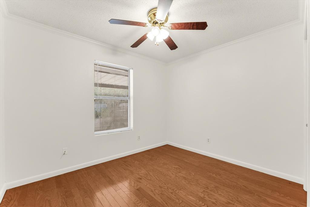 Hardwood flooring, crown molding, window with blinds, ceiling fan with light fixture, and white painted walls