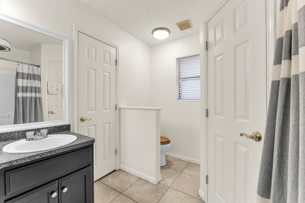 Vanity with an oval sink, dark countertop, and mirror