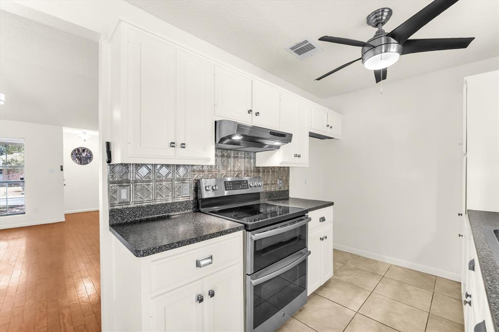 Kitchen featuring white cabinetry, dark speckled countertops, a double-oven range, and a decorative backsplash