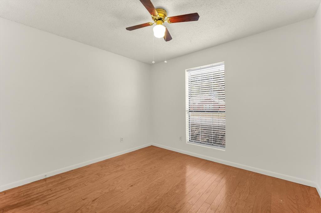 Wood-finish flooring, ceiling fan with integrated lighting, and a window with horizontal blinds
