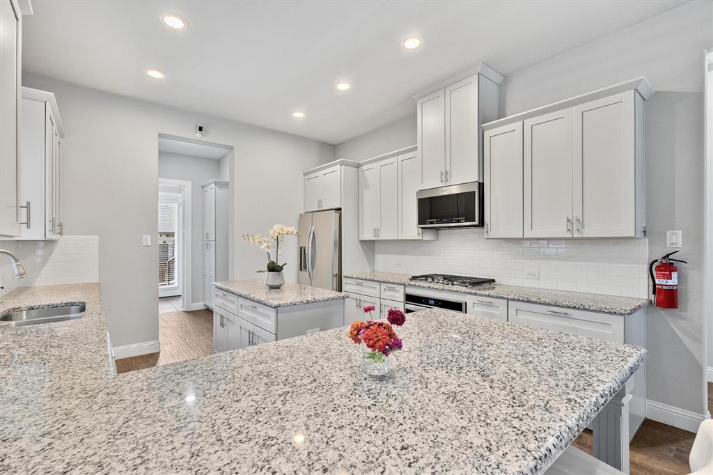 Contemporary kitchen featuring white cabinetry, light-toned countertops, stainless steel appliances, a white subway tile backsplash, and recessed lighting
