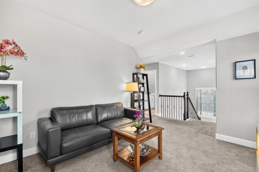 Carpeted landing with a decorative iron railing and recessed lighting