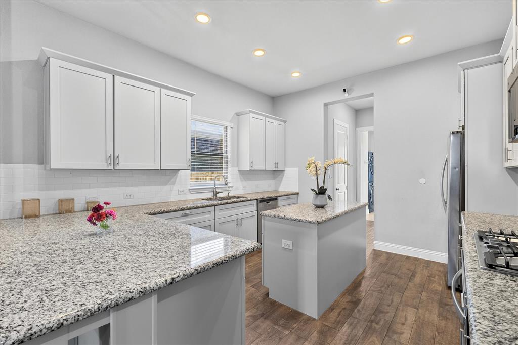 Kitchen featuring light-toned cabinetry, a central island, granite countertops, wood-finish flooring, and recessed lighting