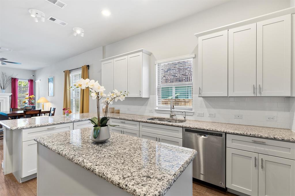 Kitchen featuring white shaker-style cabinetry, granite countertops, stainless steel dishwasher, and an undermount sink
