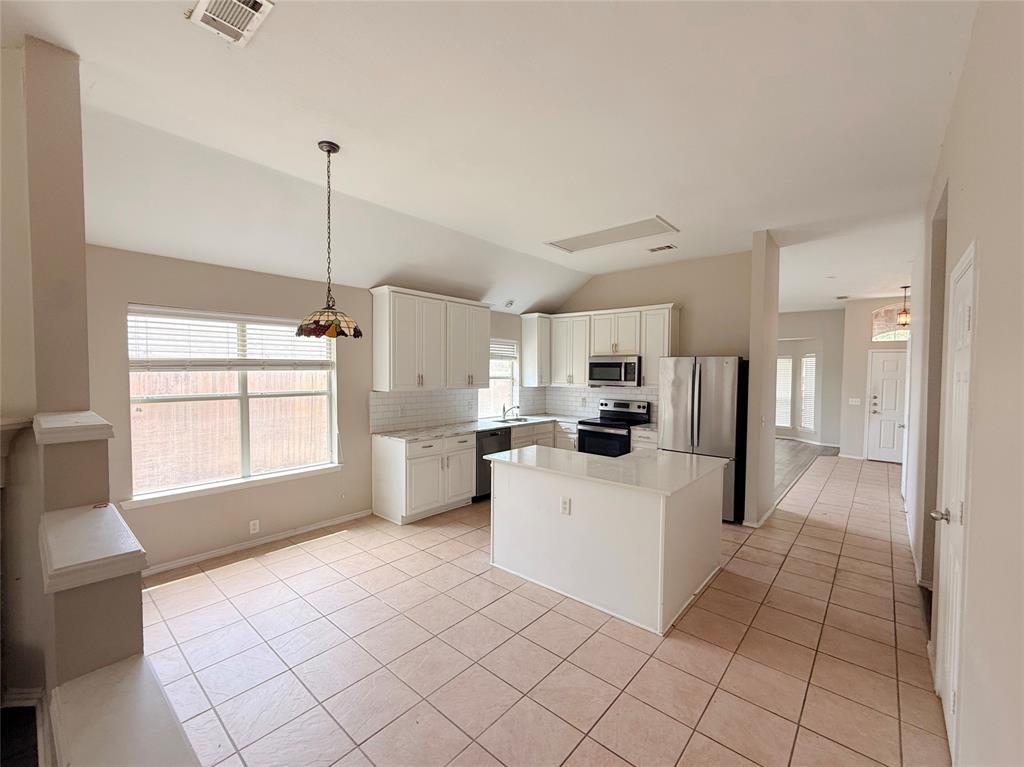 Kitchen featuring white cabinetry, stainless steel appliances, a center island, and tile flooring