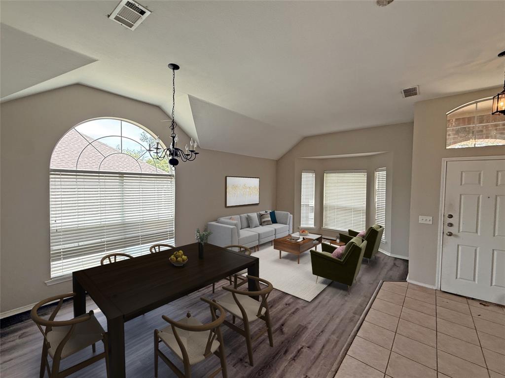 Vaulted ceilings, wood-finish flooring, a decorative chandelier, a large arched window, and a white paneled entry door