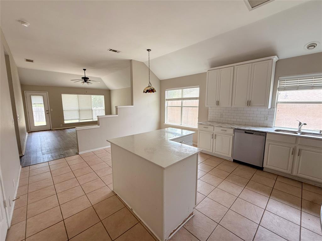Kitchen featuring an island, white cabinetry with silver hardware, subway tile backsplash, and stainless steel dishwasher