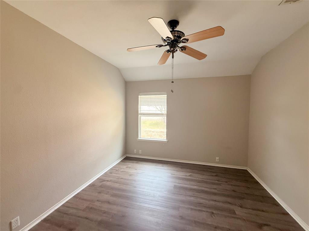 Vaulted ceiling with a ceiling fan, wood-finish flooring, and neutral wall tones