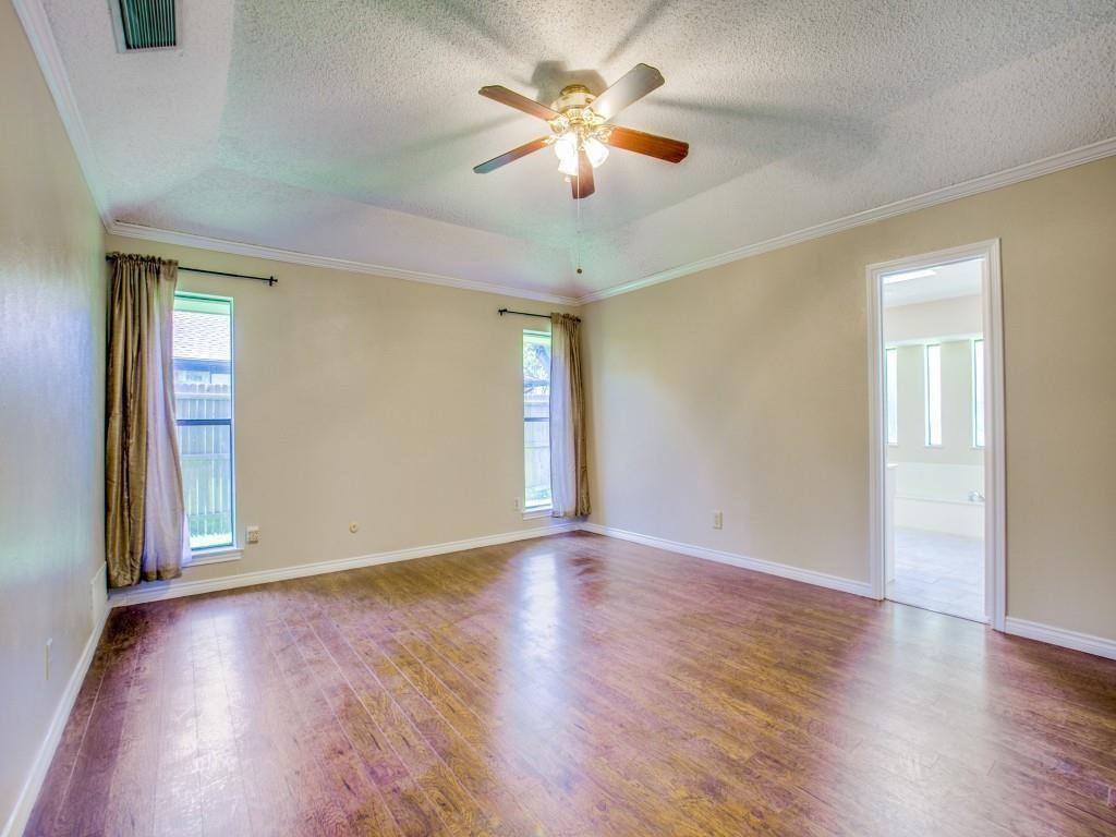 Tray ceiling with crown molding, wood-finish flooring, and a ceiling fan with integrated lighting