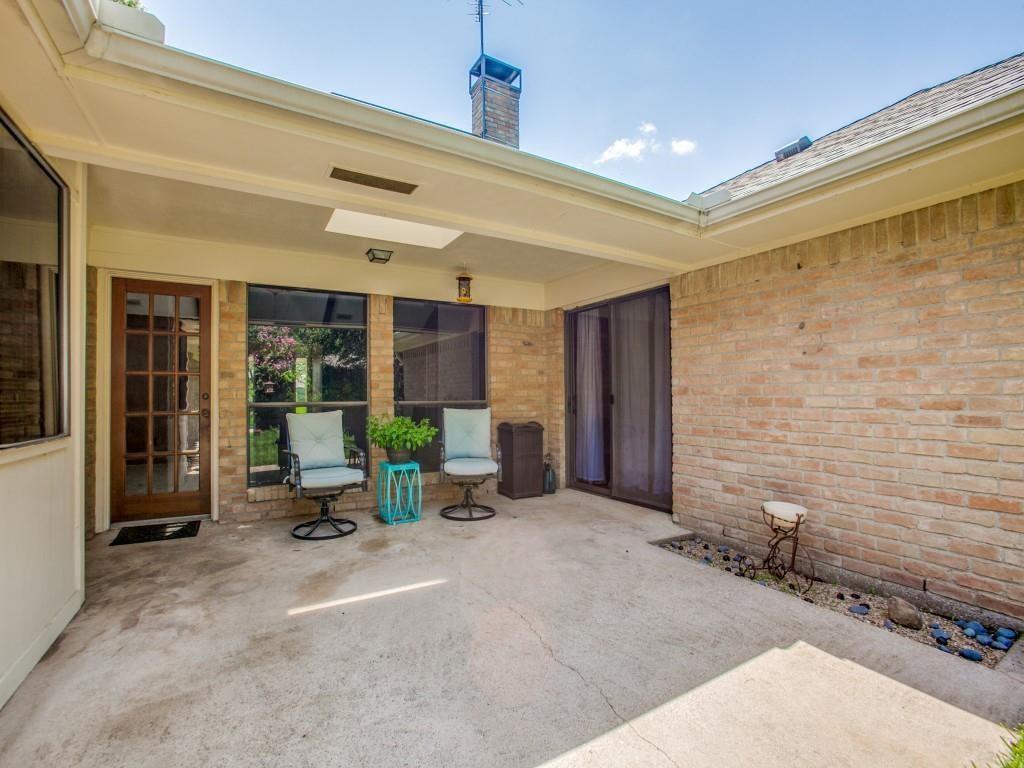 Covered concrete patio with brick exterior, a wood-frame glass panel door, and a sliding glass door