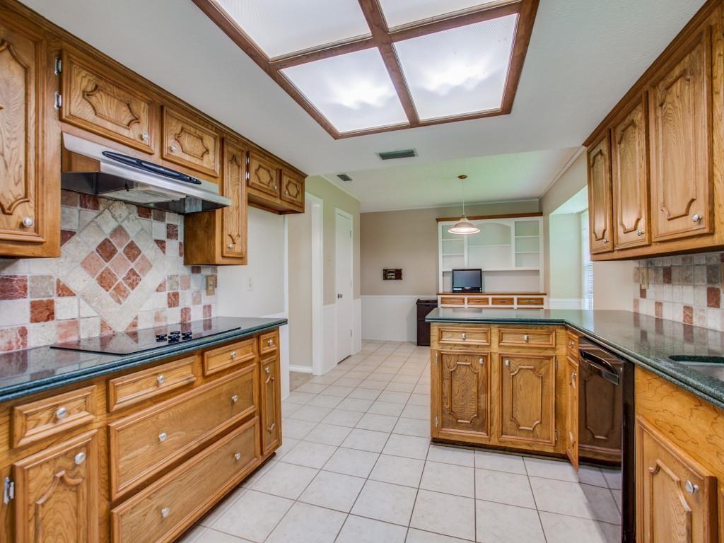 Kitchen with wood cabinetry, tiled flooring, built-in cooktop, and a ceiling-mounted light fixture