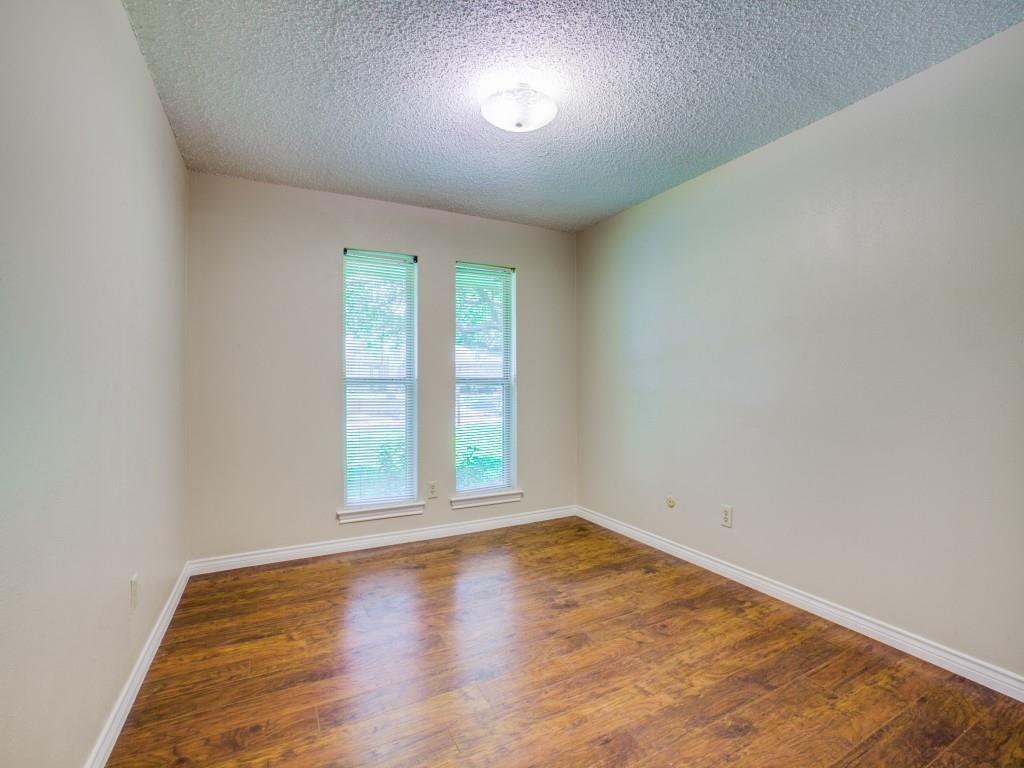 Neutral wall paint with wood-finish flooring, two large windows, and a flush mount ceiling light fixture