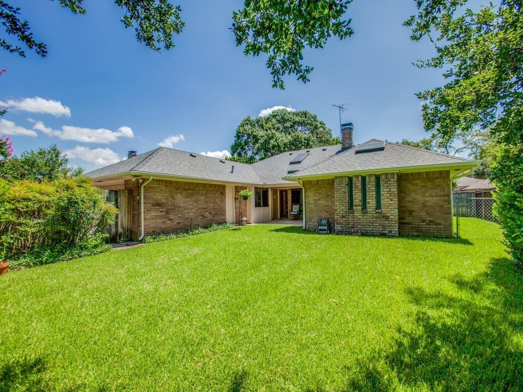 Expansive lawn area with mature landscaping, brick exterior, and a shingled roofline