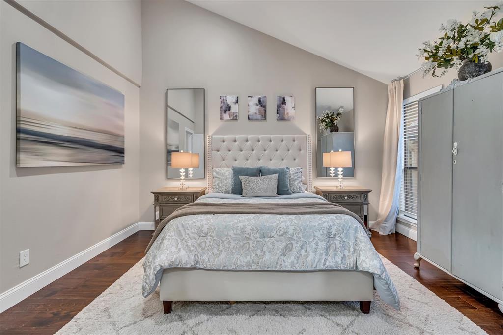 Vaulted ceiling, dark wood-finish flooring, built-in window blinds, and black out curtains.