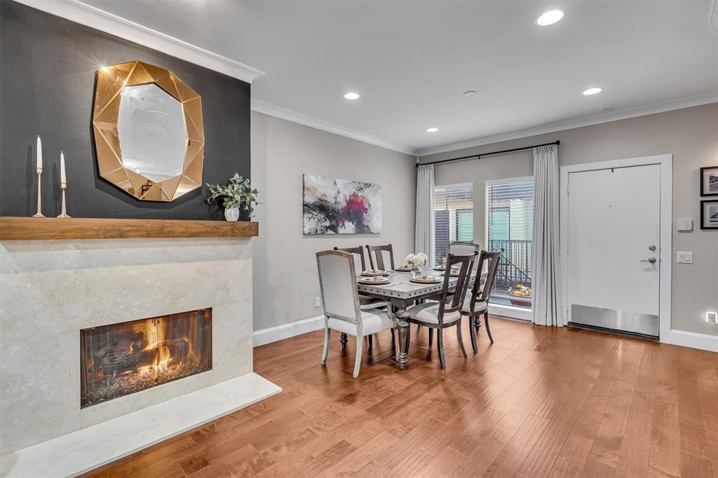 Hardwood flooring throughout, stone-clad fireplace with wood mantle, recessed lighting, and crown molding.