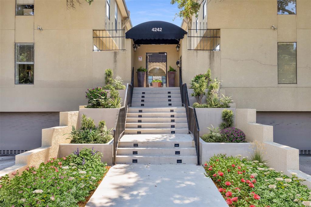 Building front exterior with a covered entry, concrete steps, wrought iron handrails, integrated planters, and surrounding landscaping