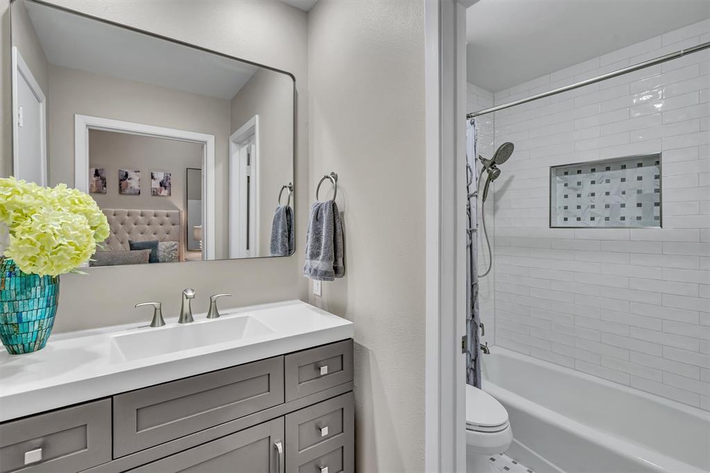 Modern primary bathroom featuring a dark wood-finish vanity, white quartz countertop, and polished chrome fixtures